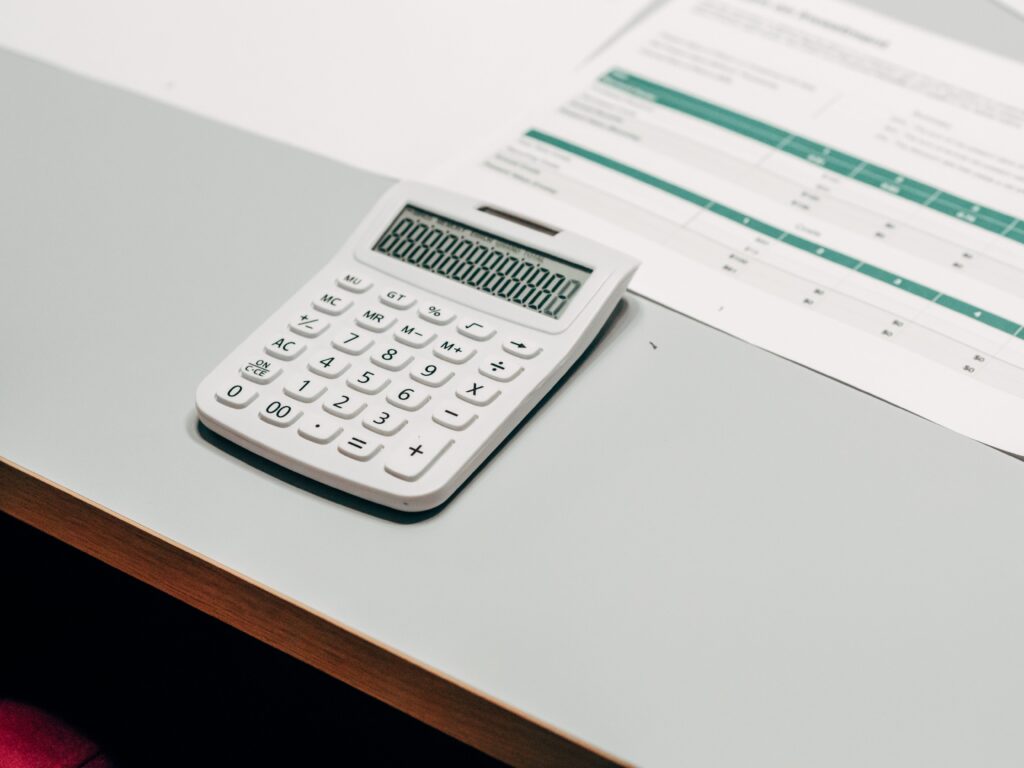 pexels photo 7688365 7688365 Close-up of a white calculator next to a financial spreadsheet on a desk.
